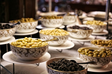 Different kinds of olives in bowls on table at buffet