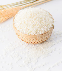 raw rice in a bamboo basket with wheat isolated on white background