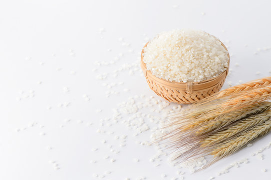 raw rice in a bamboo basket with wheat isolated on white background