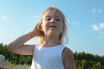 Blonde cute little child girl posing in countryside, summer village