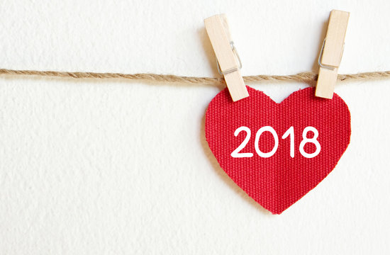 Red fabric heart with  2018 word hanging on the clothesline over white wall background, new year template