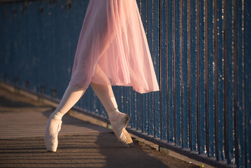 Woman in pink costume and pointe shoes dancing on a bridge