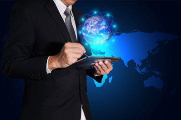 Businessman working with tablet and glowing node digital world on light blue earth map background as business technology, innovation and globalization concept. Elements of this image furnished by NASA