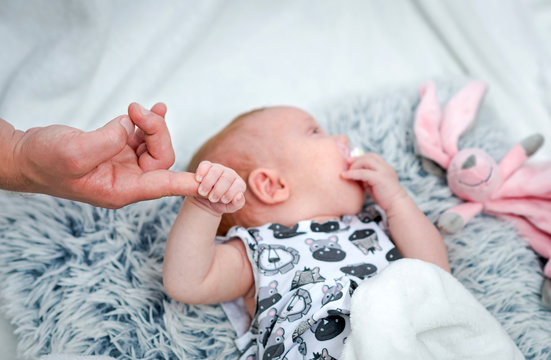 Newborn girl holding fathers finger and sleeping