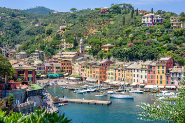 Beautiful aerial daylight view from top to ships on water and buildings in Portofino city of Italy. Tourists walking on sidewalk. Top view