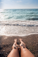 Fototapeta na wymiar Shells on the woman's feet at the sea shore