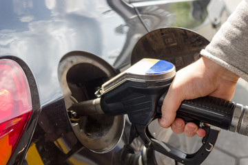 Close-up of hand refueling car's tank by holding petrol pump nozzle