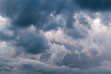 In the sky the storm clouds, and the clouds. Bad weather. Strong wind and feeling the rain. The clouds are dark blue. The clouds are lit by sunlight.