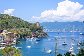 Fototapeta na wymiar Beautiful aerial daylight view from top to ships on water and buildings in Portofino city of Italy. Tourists walking on sidewalk. Top view