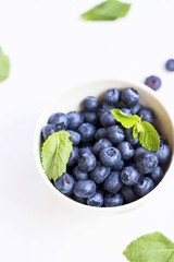Blueberries fruits closeup in a bowl with green mint leaves