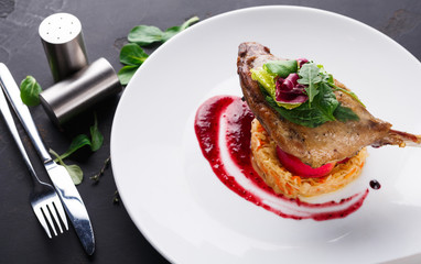 Restaurant meals. Duck confit with vegetables on black background