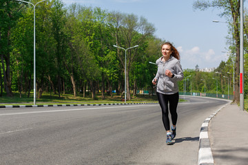 Young woman jogging on road, copy space © Prostock-studio