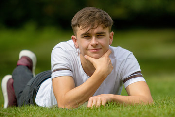 Naklejka premium Teenage boy laying on grass on a summers day
