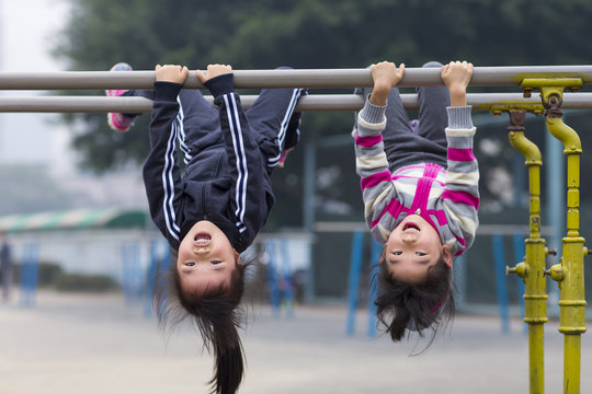 Lovely two Little GIrls hang on parallel bars