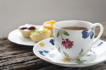Obraz na płótnie Canvas A cup of tea and fruit tarts on the table