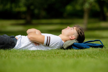 Teenage boy laying on grass on a summers day