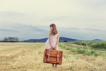 Little girl in classic dress with travel suitcase