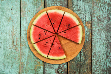 Fresh ripe watermelon cut in segments on shabby green table