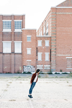 Young woman doing anti gravity lean in front of brick buildings