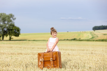 Little girl in classic dress with travel suitcase