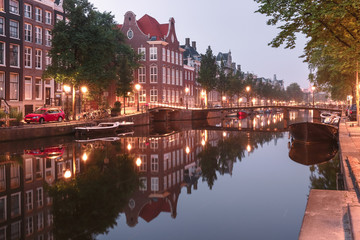 Amsterdam canal Kloveniersburgwal with typical dutch houses, bridge and houseboats during morning blue hour, Holland, Netherlands.