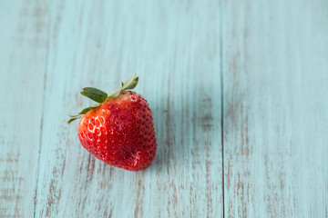 Single Strawberry on Blue Wood Background