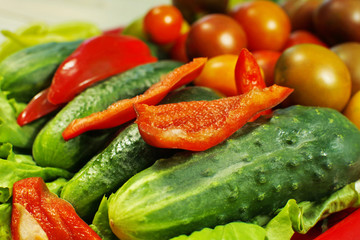 Assorted raw organic vegetables for healthy eating. Tomatoes, cucumbers, peppers and lettuce close up.