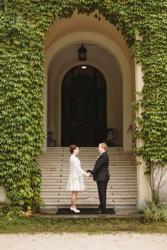 Newly wedded couple holding their hands, staying in front of chu