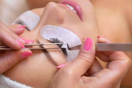 Fototapeta Beautiful Woman with long eyelashes in a beauty salon. Eyelash extension procedure. Lashes close up