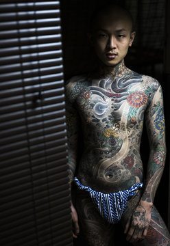 Japanese male in a tattoo studio exposing his tattooed body