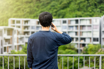 A man talking on smart phone for business looking on building through the balcony. Always stay connected concept