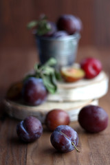 Plums in a small bucket on a wooden background