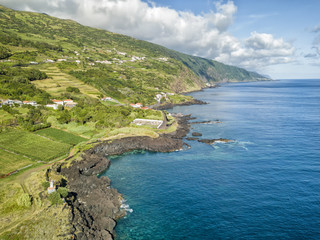 Aerial shot showing the small village of Manadas and the blue waters of the Atlantic ocean on Sao Jorge, Portugal.