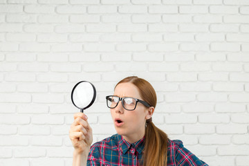 Funny expression. Shocked woman looking through a magnifying glass.