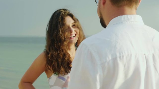 Young woman with her husband dancing on the beach. 4K slow motion video