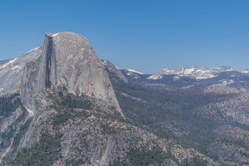Side view of half dome, blue sky and surrounding wilderness, from glacier point, in Yosemite national park
