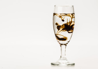 Dark brown food coloring diffuse in water inside wine glass with empty copyspace area for slogan or advertising text message, over isolated grey background. 