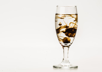 Dark brown food coloring diffuse in water inside wine glass with empty copyspace area for slogan or advertising text message, over isolated grey background. 