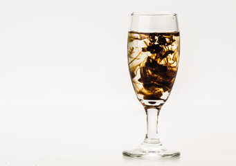 Dark brown food coloring diffuse in water inside wine glass with empty copyspace area for slogan or advertising text message, over isolated grey background. 