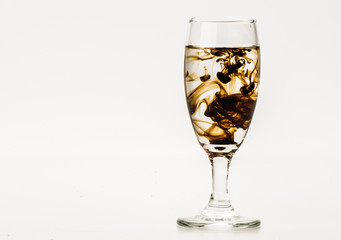 Dark brown food coloring diffuse in water inside wine glass with empty copyspace area for slogan or advertising text message, over isolated grey background. 