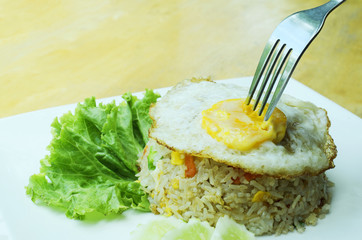 Fried Egg with a fork on Crab Fried Rice on white dish for Thai food style concept