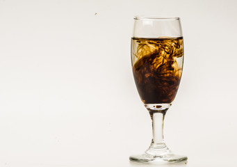 Dark brown food coloring diffuse in water inside wine glass with empty copyspace area for slogan or...