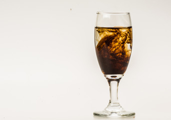 Dark brown food coloring diffuse in water inside wine glass with empty copyspace area for slogan or advertising text message, over isolated grey background. 