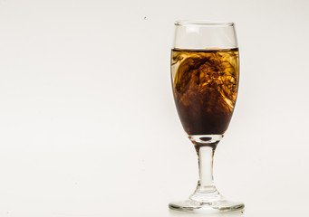 Dark brown food coloring diffuse in water inside wine glass with empty copyspace area for slogan or advertising text message, over isolated grey background. 