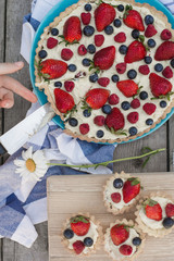 Fruit tart strawberries, blueberries, raspberries on wood in the garden view from above