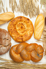 Assortment of baked bread on white wooden table background