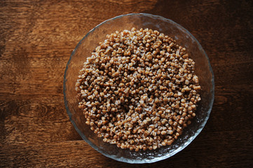 A large plate of boiled buckwheat on a brown wooden texture table