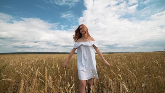 red-haired girl in a field of wheat in a white dress smiles a lovely smile , a perfect picture for advertising in the style lifestyle