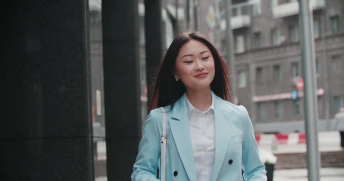 beautiful young business Asian woman goes to work in the business district with coffee to go, slow motion