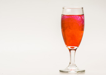 mixture of food coloring diffuse in water inside wine glass with empty copyspace area for slogan or advertising text message, over isolated grey background. 